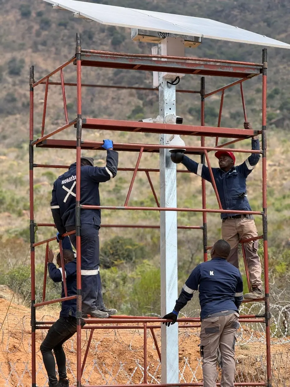 Installation team working beneath a solar panel at a remote site